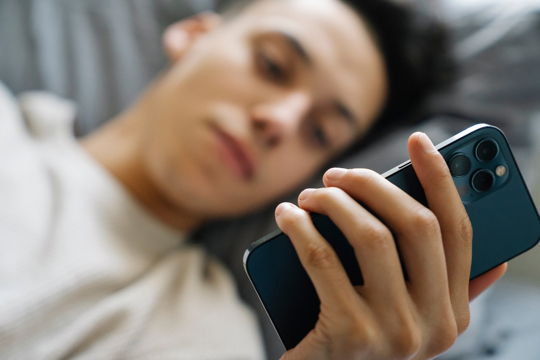 Young guy browsing mobile phone on bed